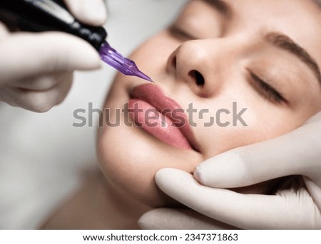 PMU Concept. Professional Permanent Makeup Artist Doing Lip Blushing Procedure To Young Woman, Tattooing Contour Of Her Lips, Closeup Shot Of Attractive Female Getting Cosmetic Tattoo In Beauty Salon Royalty-Free Stock Photo #2347371863