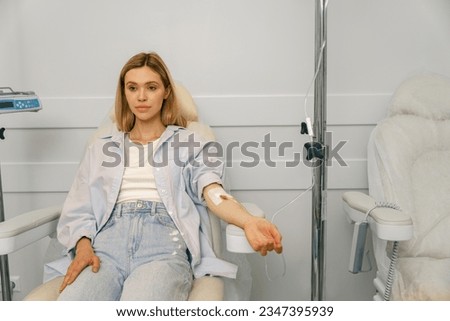 Woman sitting in armchair while receiving IV infusion in hospital. High quality photo Royalty-Free Stock Photo #2347395939