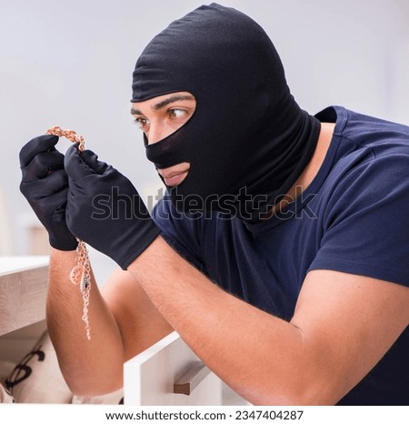 Robber wearing balaclava stealing valuable things Royalty-Free Stock Photo #2347404287