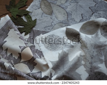 Fabric with leaves pattern and dried plants on the wooden table. Concept of eco print, botanical or natural printing