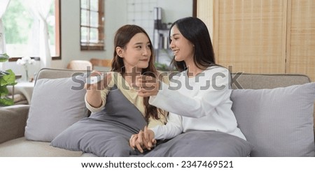 Asian lesbian woman couple enjoy watch TV together in house and feel happy watch movie on television. Homosexual-LGBTQ concept.