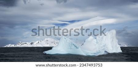 Mountainous cloudscape; Antarctica; Pink light on clouds; Scooped blue iceberg; Sculpted berg and brash ice; Sculpted berg reflection; Small berg with blue underwater tongue; Small iceberg with cloud