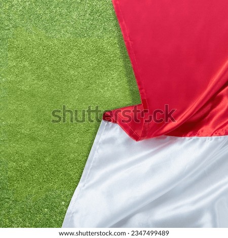 The red and white flag of Indonesian flag with green grass background
