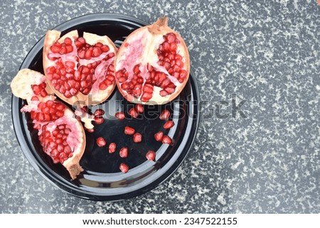 A closeup selective focus picture of the tropical fruit pomegranate kept in a black plate
