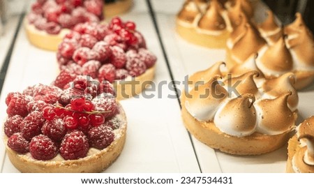 Different berry tarts and lemon meringue tart with curd on the table. Delicious pastries. Tasty passion fruit and lemon tartlet. Food concept for restaurant and bakery shop