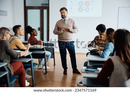 University professor talking to group of students during class in lecture hall. Royalty-Free Stock Photo #2347571169