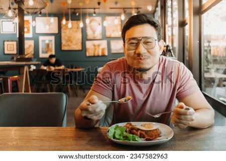 Asian men with a beard wear eyeglasses and enjoy eating in the restaurant. Royalty-Free Stock Photo #2347582963