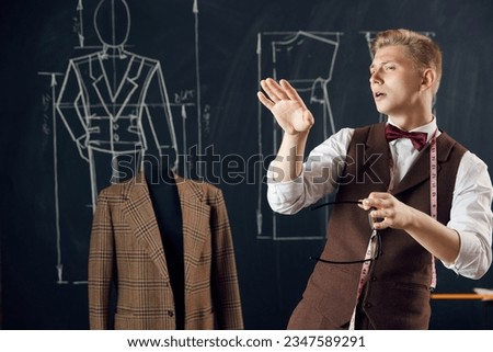 Young man, talented fashion designer attentively looking, visualization future clothing line. Fashion atelier. Concept of fashion, profession, creativity, occupation, hobby, business