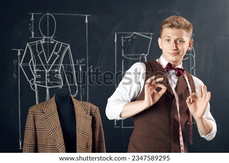 Young delightful man, fashion designer feeling happy and positive about made suit, perfectly looking cloth model. Concept of fashion, profession, creativity, occupation, hobby, business