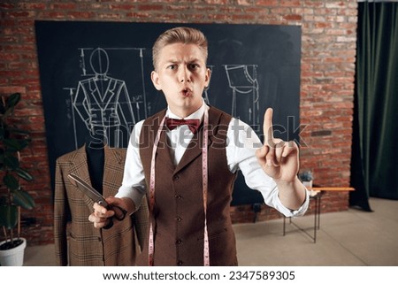 Young man, fashion designer with scissors and measuring tape raising finger up. Education in fashion industry. Concept of fashion, profession, creativity, occupation, hobby, business