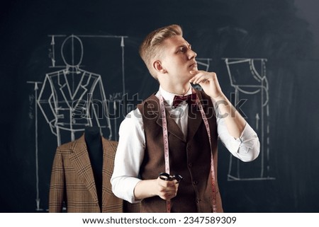 Young man, fashion designer standing in atelier with thoughtful face, generating new clothing collection ideas. Concept of fashion, profession, creativity, occupation, hobby, business
