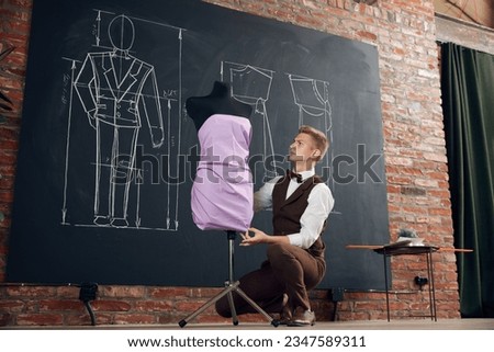 Talented man, fashion designer working in ateliers, creating beautiful dress, making measurements on mannequin. Concept of fashion, profession, creativity, occupation, hobby, business
