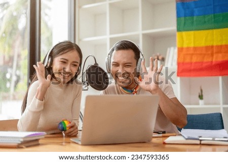 An attractive and happy Asian gay man enjoys reading comments online, talking, and streaming live podcasts online with his female colleague in the studio.