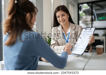 A gorgeous and professional Asian businesswoman or female financial consultant is having a meeting with a female client in the office to sign a contract. investment, real estate agent, banker