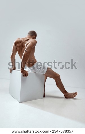 Handsome young man with blonde hair, relief, muscular, strong shirtless body posing in underwear against grey studio background. Concept of male natural beauty, body care, health, sport, fashion, ad Royalty-Free Stock Photo #2347598357