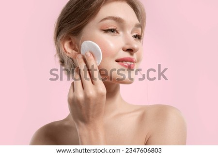 Beautiful woman removes make-up and cleanses her skin with cotton pads on a pink background Royalty-Free Stock Photo #2347606803