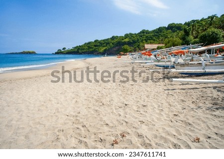 Virgin Beach with traditional wooden outrigger boats on the sand in Karangasem Regency, Bali, Indonesia.