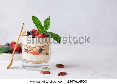 Sweet dessert in a glasses with berries, mint, nuts, whipped cream and biscuit with a spoon. Vegan, sugar, gluten and lactose free. Berry dessert, cheesecake, trifle, mouse in a glass. Copy space. Royalty-Free Stock Photo #2347614903