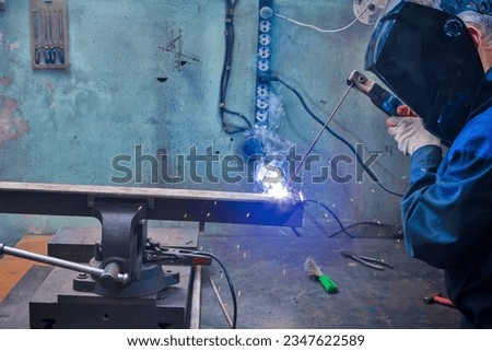 Closeup of Professional Male Welder in Protective Mask During Welding Process of Metal Rod At Factory.Horizontal Shot Royalty-Free Stock Photo #2347622589