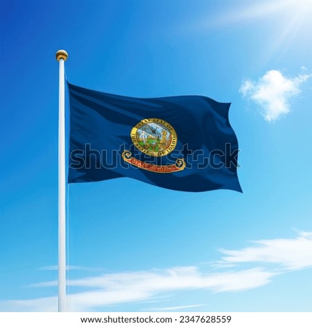 Waving flag of Idaho is a state of United States on flagpole with sky background.
