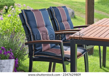 Modern chairs in the beautiful summer terrace and blooming garden