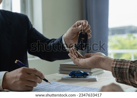 Company employees are handing out car keys to tenants after discussing the details and rental terms along with the tenant who signed the contract. Royalty-Free Stock Photo #2347633417