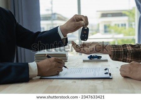 Company employees are handing out car keys to tenants after discussing the details and rental terms along with the tenant who signed the contract. Royalty-Free Stock Photo #2347633421
