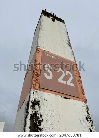 the pole that shows the level for the parking lot in the mall. the pole shows level 3, S 22