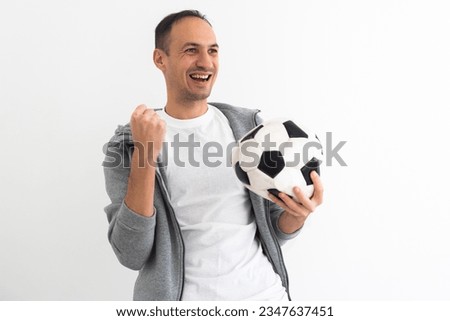 Handsome player man playing soccer holding football ball over background with surprise face pointing finger to himself