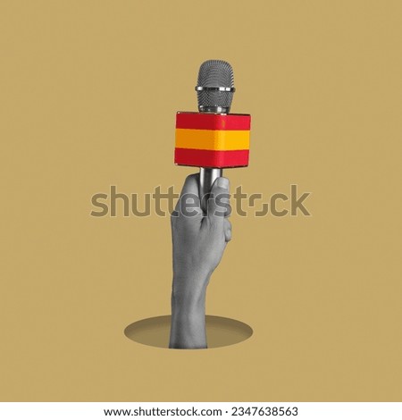 the hand of a man, in black and white, holding a microphone patterned with the flag of spain, on a pale brown background