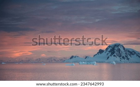 Sunlit berg, shadowed mountainside; Sunlit mist, on the mountain; Sunlit snow, ridge reflection; Sunset clouds, over brash ice; distant icebergs; Errera Strait; Dorian Bay, blue bergs; Antarctica