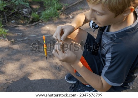 A teenager sets up a lure to catch fish. Sport fishing on the river in summer.