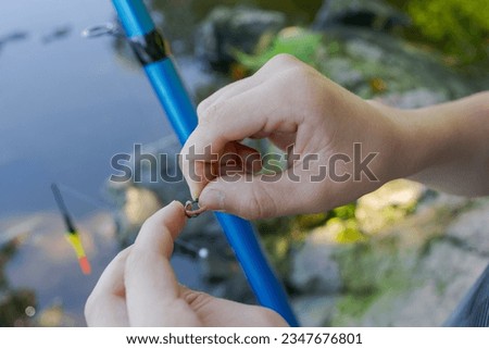 Close-up of a teenager's hands putting bait on a fishing hook Sport fishing on the river in summer.