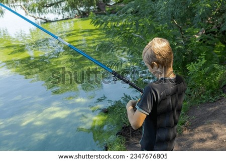 A boy casts a fishing rod to catch fish. Sport fishing on the river in summer.