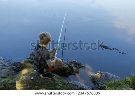 A teenager on a fishing trip waiting for a nibble of fish. Sport fishing on the river in summer.