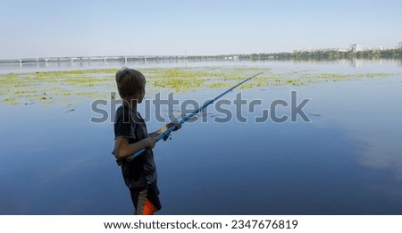 A teenager on a fishing trip keeps a close eye on the nibble. Sport fishing on the river in summer.