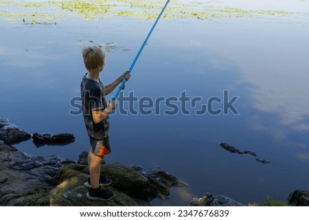 A boy with a rod in his hands on the river catching fish. Sport fishing on the river in summer.