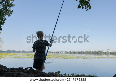 A teenager prepares to go fishing on the river. Sport fishing on the river in summer.