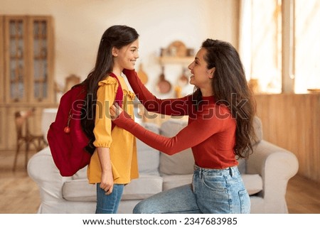 Back to School. Happy middle eastern mom preparing preteen schoolgirl daughter with backpack for first school day at home, looking at kid and encouraging her to enjoy classes in the morning Royalty-Free Stock Photo #2347683985
