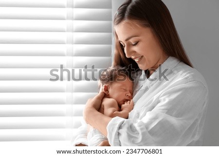 Mother holding her cute newborn baby indoors. Space for text Royalty-Free Stock Photo #2347706801