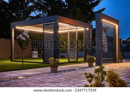 Stunning night photo of a luxurious outdoor pergola, boasting exquisite design with LED panels and lighting. Fully controllable via mobile, set in the garden of an upscale family home. Royalty-Free Stock Photo #2347717539