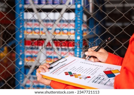 A worker is checking on the hazardous chemical material information form with background of chemical storage area at the factory place. Industrial safety working action. Selective focus. Royalty-Free Stock Photo #2347721113