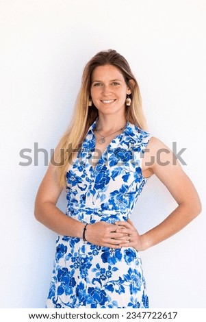 Cute blond girl portrait with blue dress smiling at camera.