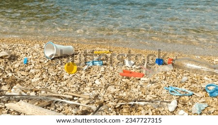 CLOSE UP: Pebble beach polluted by plastic waste washed up by the Adriatic Sea. Sad sight for an all too common occurrence on beautiful seashores. Coastal landscape where garbage remains accumulate. Royalty-Free Stock Photo #2347727315