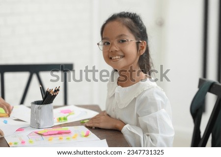 A cute little boy with glasses learning to draw happily.