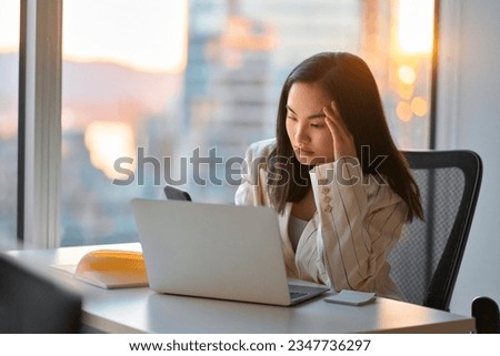 Young busy stressed upset Asian business woman holding cellphone using mobile phone, looking at smartphone feeling tired frustrated reading bad news on financial market working in office. Royalty-Free Stock Photo #2347736297