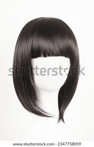 Natural looking black wig on white mannequin head. Medium length straight hair with bangs on the metal wig holder isolated on white background, front view Royalty-Free Stock Photo #2347758059