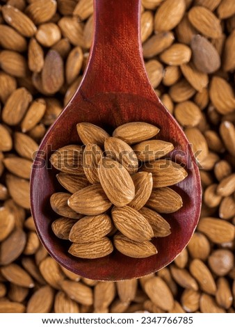 Dried almonds. Almond kernels lie in wooden spoon. Top view of nuts close-up. Advertising photography for marketplaces or online stores.