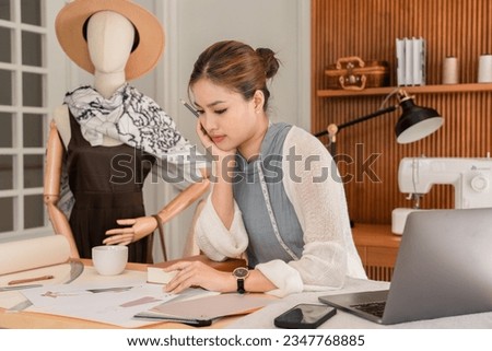 Asian tailor women thinking design new fashion collection and choosing color sample for sketching.