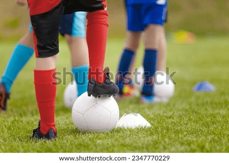 Soccer training drill for kids. Legs of football players attending soccer class. Children playing sports outdoor. School kids in soccer cleats kicking classic soccer balls Royalty-Free Stock Photo #2347770229